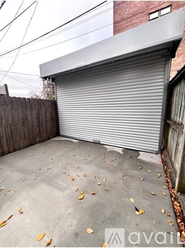 A closed grey garage door is on the left side of a concrete driveway.