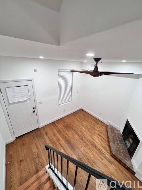 A room with a ceiling fan and wooden floors.