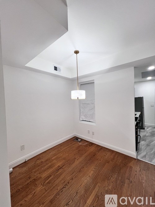 A room with wooden flooring and a hanging light fixture.