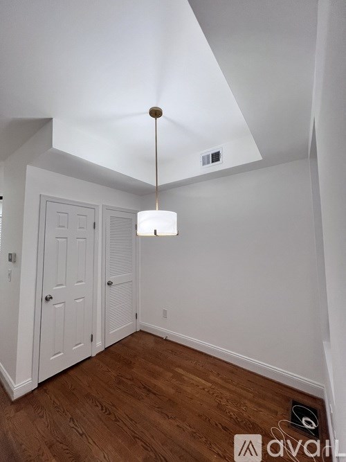 A white room with a wooden floor and a light hanging from the ceiling.