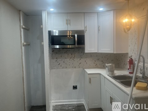 A kitchen with white cabinets and a stainless steel microwave above the stove.