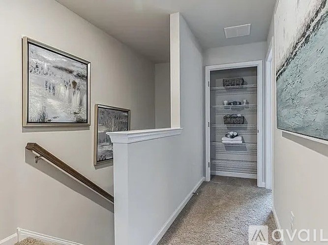 A hallway with a staircase and two pictures on the wall.