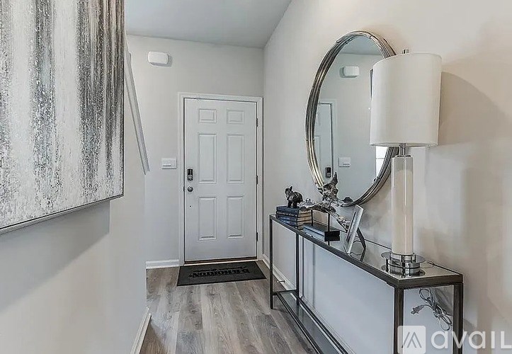 A bathroom with a white door, a mirror, a shelf with a candle, and a lamp.