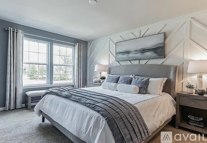 A bedroom with a large bed and a window with curtains.