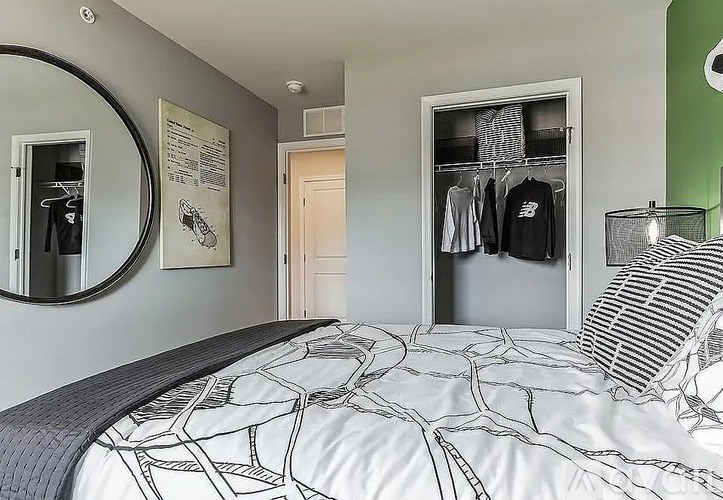A bedroom with a bed and a mirror on the wall.