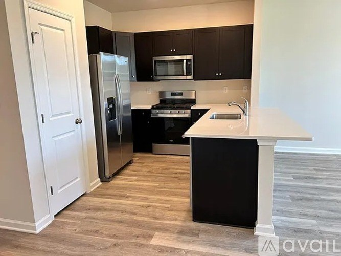 A kitchen with black cabinets and a white island.