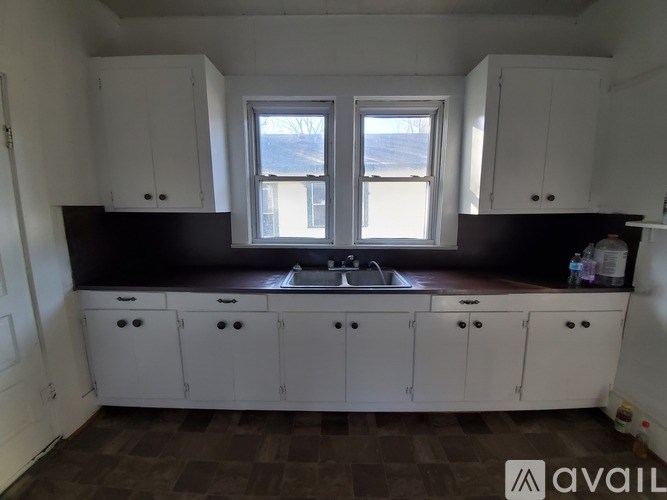 A kitchen with white cabinets and a window.
