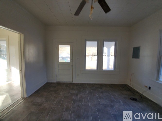 A room with a ceiling fan and three windows.