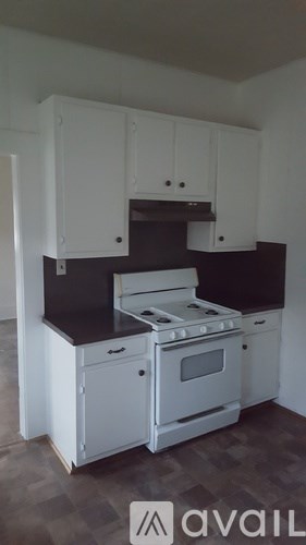 A kitchen with white cabinets and a black countertop.