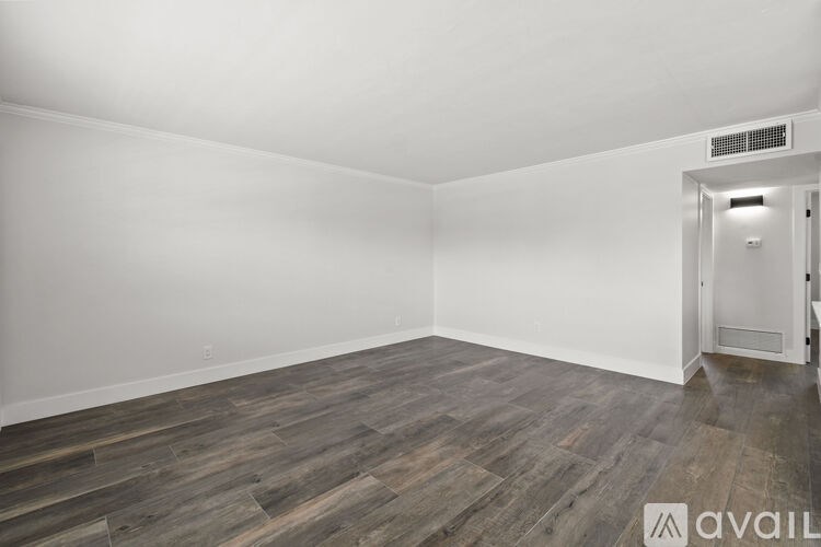 A room with wooden flooring and a white wall.