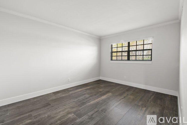 A room with wooden flooring and a window with bars on it.