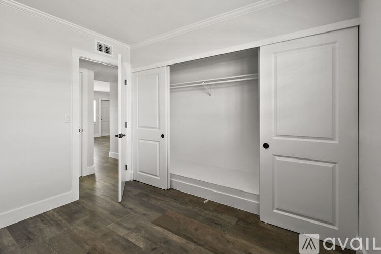 A room with white walls and a wooden floor with a door on the right.