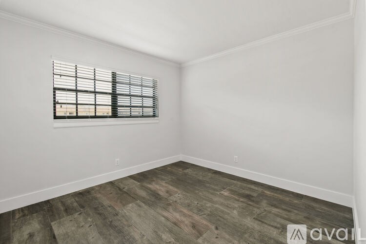 A room with wooden flooring and a window with blinds.