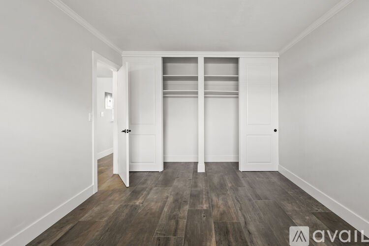 A room with a white door and a wooden floor.