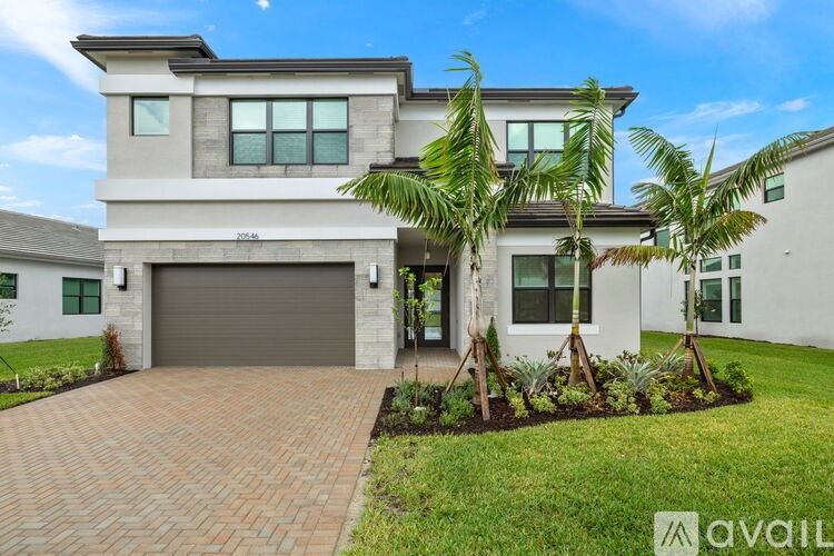 A modern house with a driveway and a palm tree in front.