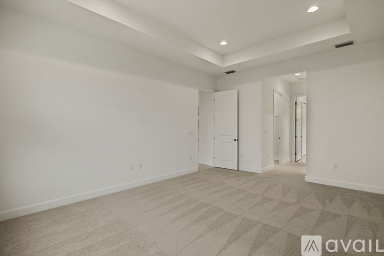 A spacious room with a carpeted floor and white walls.