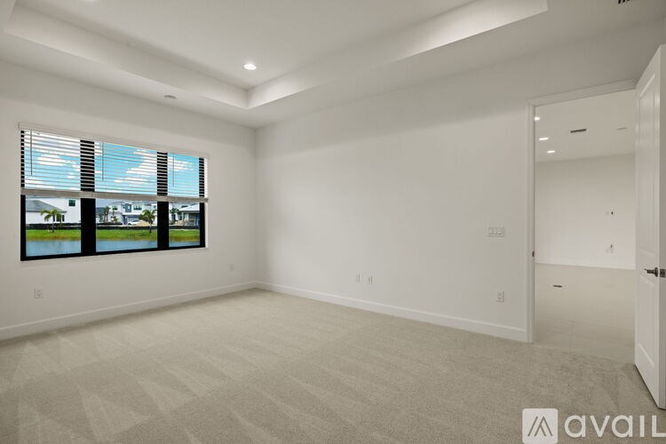 A spacious empty room with a window overlooking a body of water.