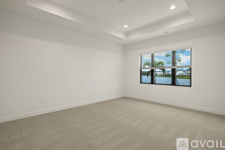A spacious room with a large window and a carpeted floor.