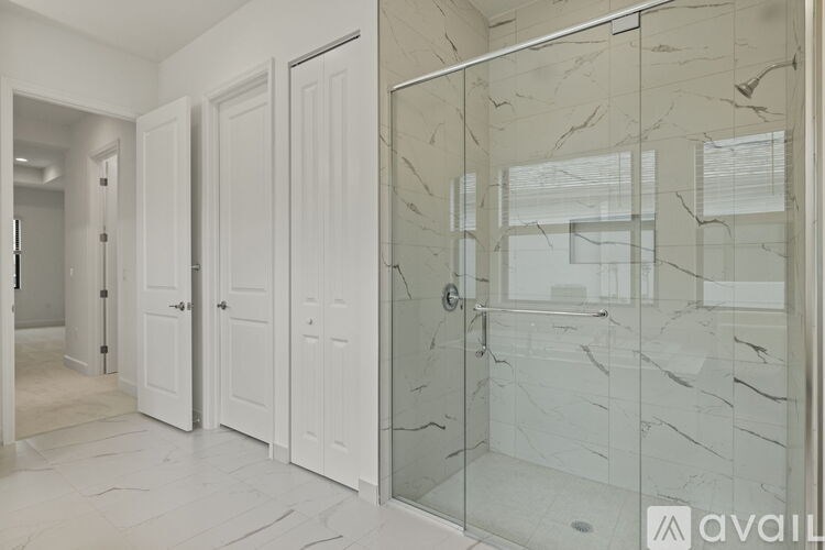 A bathroom with marble tiles and a glass shower door.