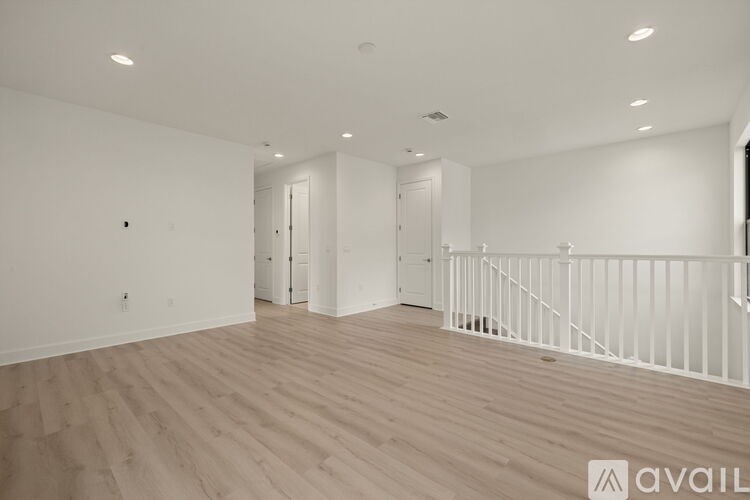 A spacious room with wooden flooring and white walls.