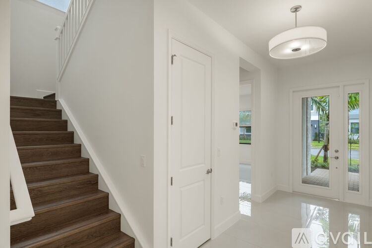 A white interior with a staircase and a door leading to a balcony.