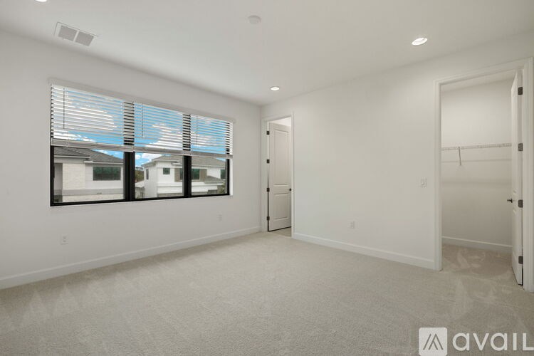 A spacious, empty room with a large window and a door leading to another room.