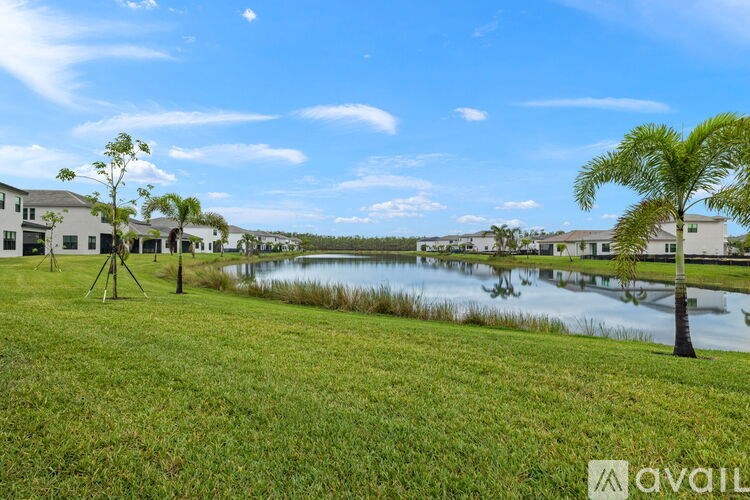 A grassy area with a lake and houses in the background.