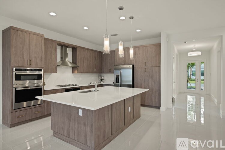 A modern kitchen with a central island and wooden cabinets.