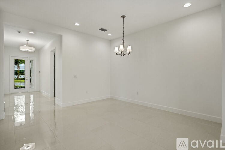 A spacious room with a chandelier and a door on the left.