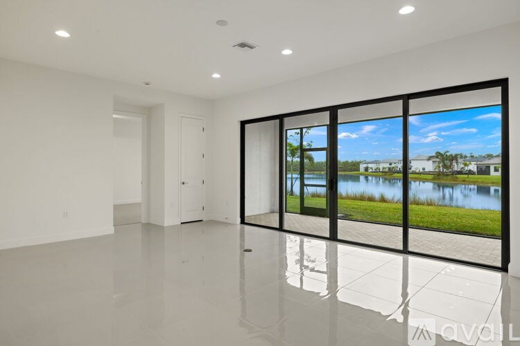 A spacious, empty room with a view of a lake through large windows.