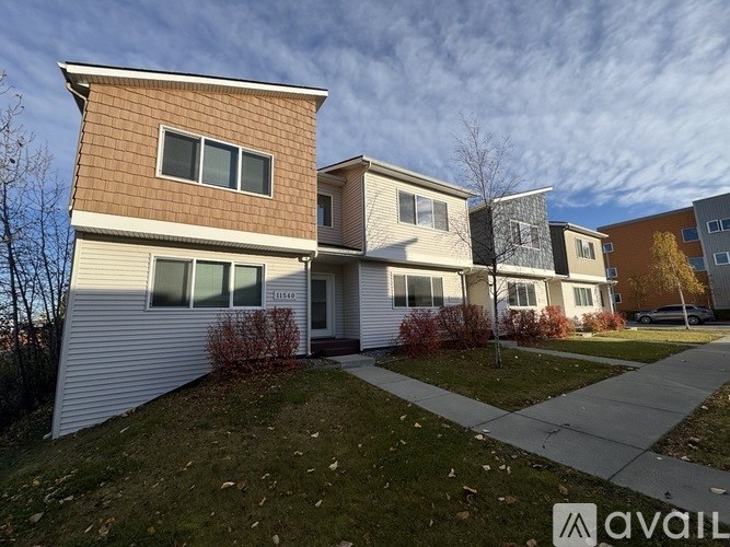 A row of houses with the first one on the left being a two story building with a tan and white exterior and the rest being one story buildings with a white and grey exterior.