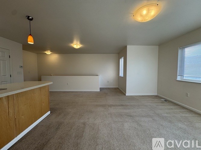 A spacious room with a carpeted floor and a window on the right side.