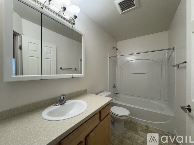 A bathroom with a sink, mirror, toilet, and shower.