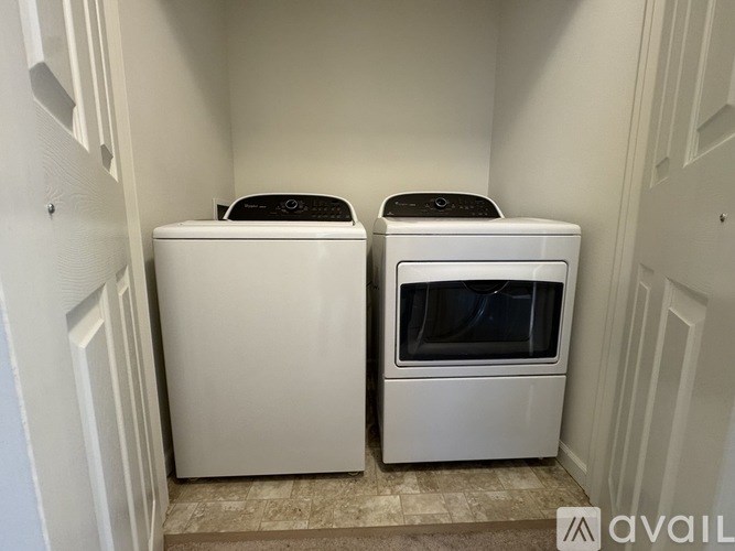 Two white front loading washing machines in a small laundry room.