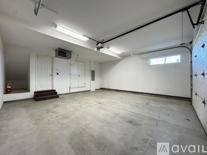 A large, empty room with a fire extinguisher on the left and a window on the right.