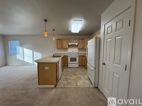 A kitchen with wooden cabinets and white appliances is available for rent.