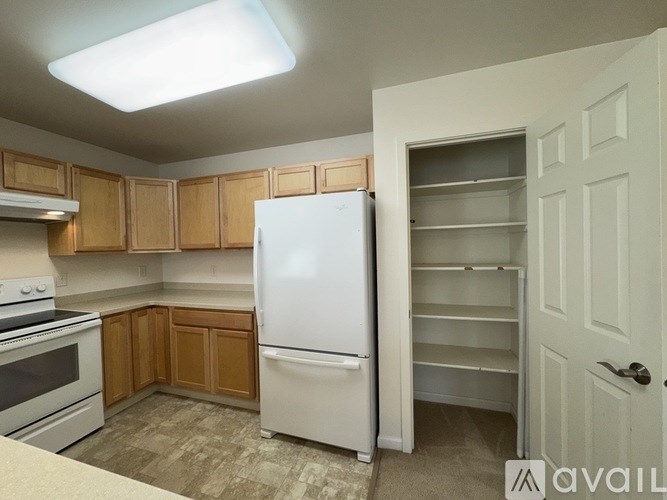 A kitchen with a white refrigerator and wooden cabinets.