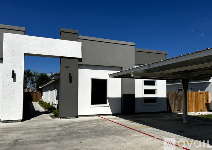 A modern house with a white and grey exterior and a red line on the driveway.