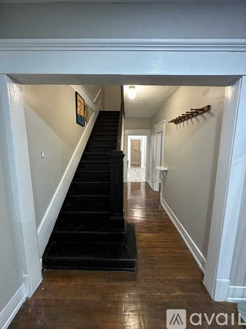 A hallway with a staircase and a rack on the wall.