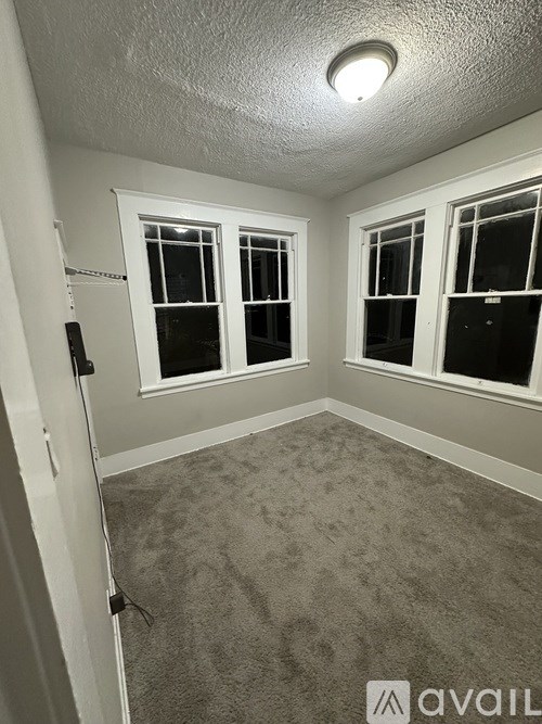 A room with carpeted floor and three windows.