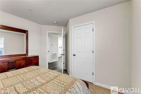 A bedroom with a bed, dresser, mirror, and door.