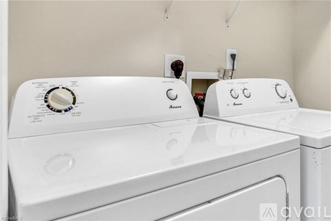 Two white front loading washing machines in a laundry room.