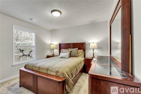 A bedroom with a bed, nightstand, and a window with blinds.