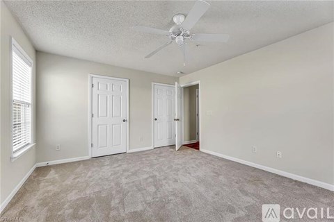 A room with a ceiling fan and carpeted floor.