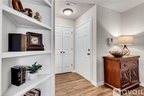 A hallway with a shelf on the left and a wooden cabinet on the right.