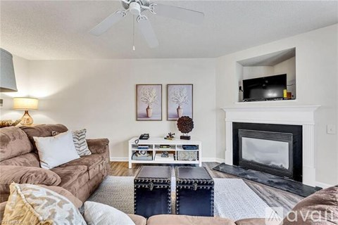 A living room with a brown couch, a white coffee table, and a fireplace.