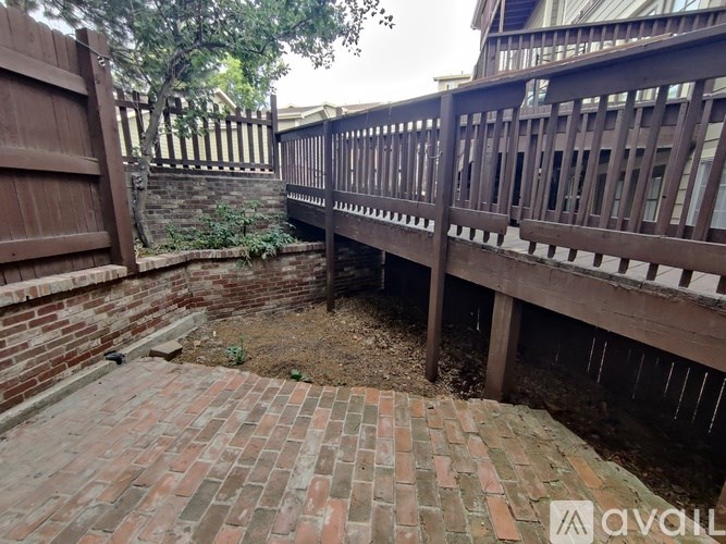 A backyard with a wooden deck and a brick patio.