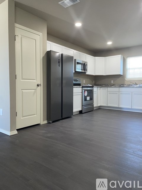 A kitchen with a black refrigerator and white cabinets.