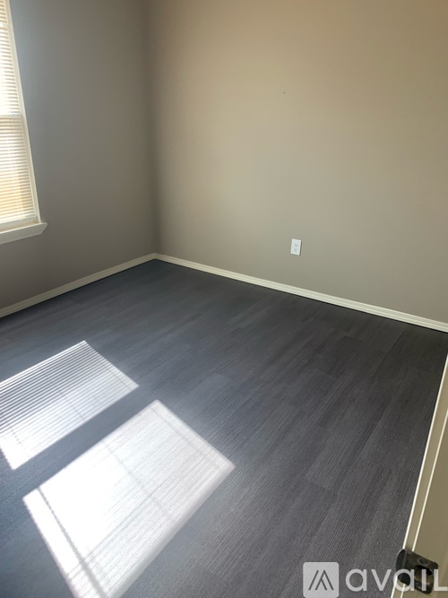 A room with a wooden floor and a window letting in sunlight.