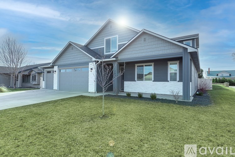 A modern house with a large front yard and a tree in the center.